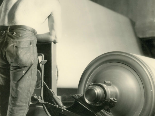 Shirtless employee working a calendar machine inside the Newton Falls Paper Mill in Newton Falls