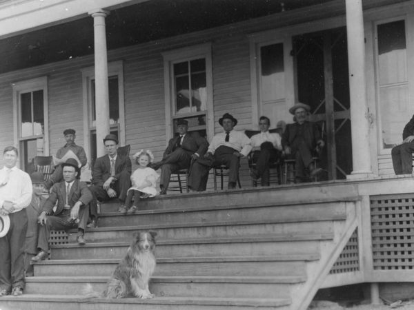 Paper plant employees and family members sit on the porch of a hotel in Pyrites