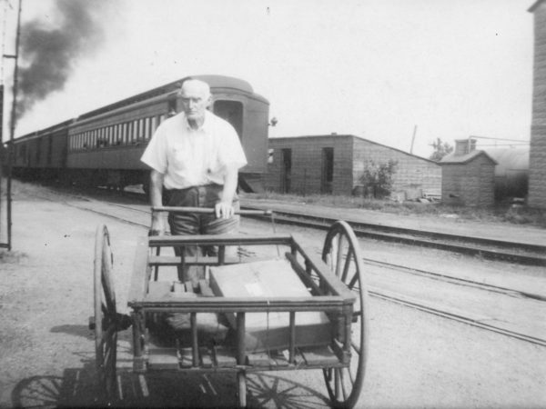 Man pushing luggage cart along station tracks in Lisbon