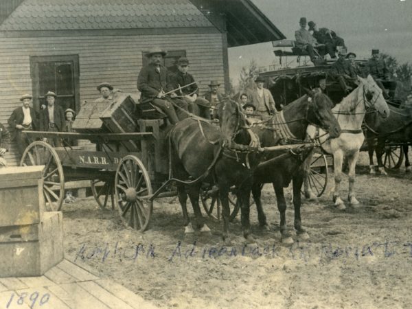 Stagecoach and station wagon parked outside station on the Northern Adirondack Railroad from Moira to Tupper Lake