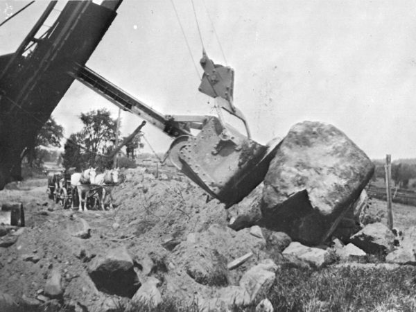 Road construction using both horses and a backhoe in Canton