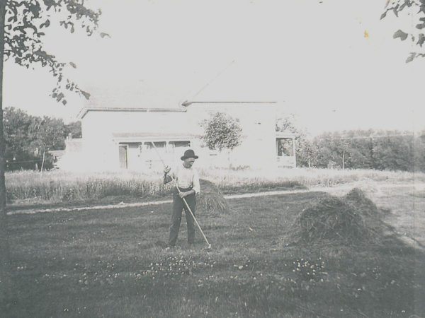 Man raking hay into haycocks by hand in Richville
