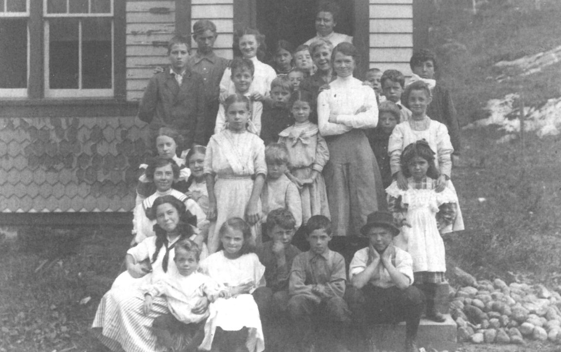 Schoolchildren and their teacher in front of the Star Lake School in