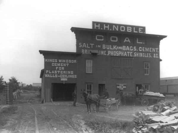 Men with horses and wagons in front of H.H. Noble Coal in Gouverneur