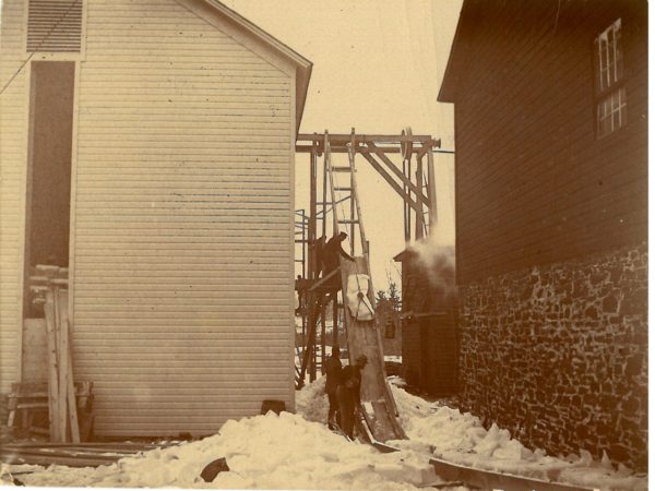 Men moving ice using ropes into ice house in Canton