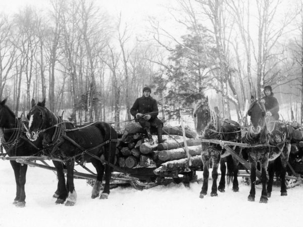 Two men driving log sleds in Hermon