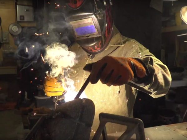 Sculptor Matt Horner using a blowtorch to heat steel in his workshop in Keene