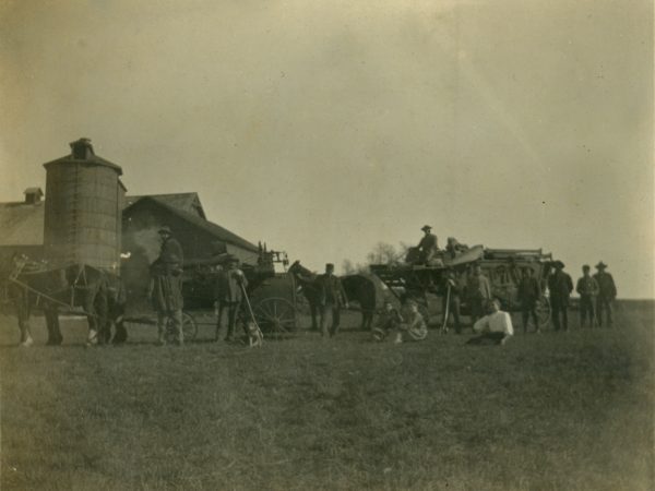 Work crew posing with threshing equipment in Hermon