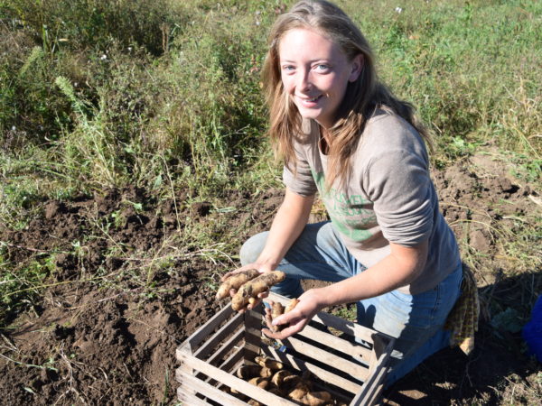 Cat Bennett posing with potatoes on her potato farm in De Peyster