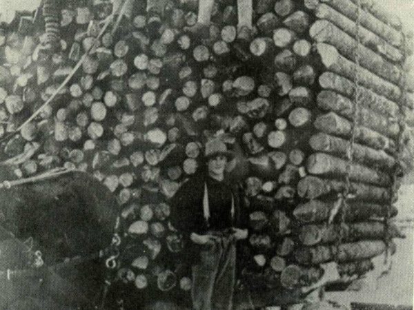 Two men on top of a sleigh load of logs on Long Lake