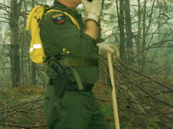 Forest ranger speaks into a walkie-talkie in Rossie