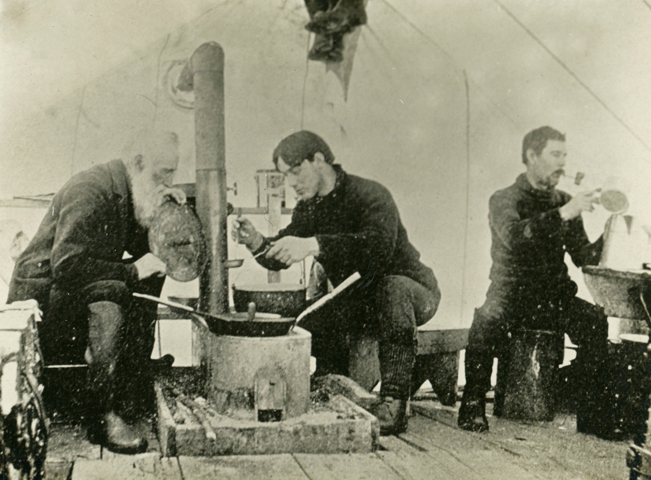 Men cooking inside a tent in Wanakena