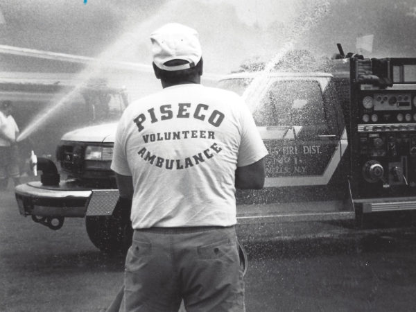 Volunteer sprays fire hose in Piseco