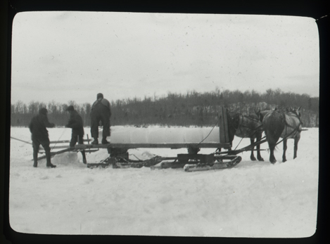 Men load ice blocks onto horse-drawn bobsled in the Adirondacks