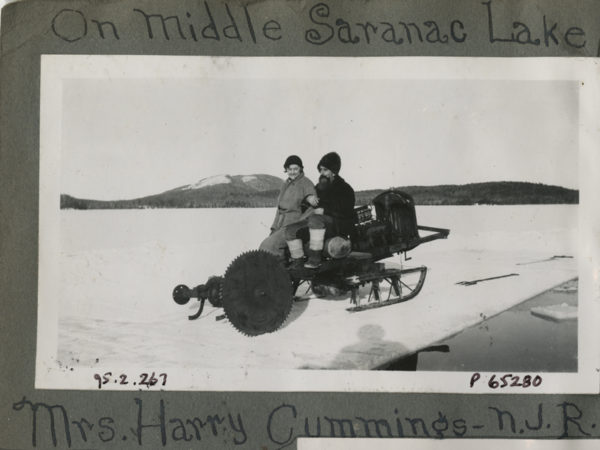 Mrs. Harry Cummings and Noah John Rondeau on motorized ice saw in Saranac Lake