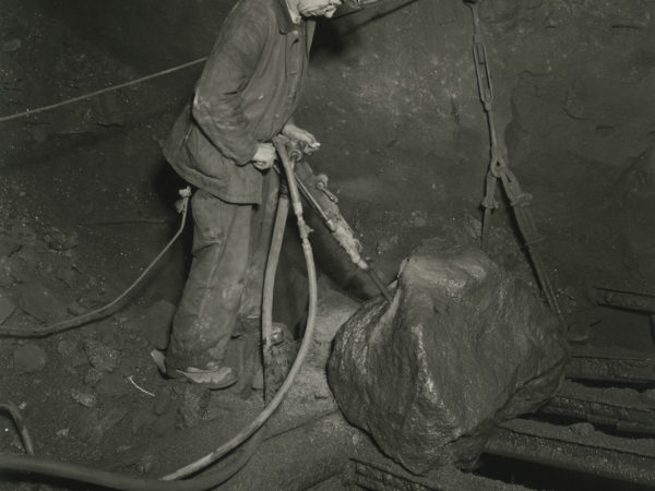 Miner drilling into ore boulder at Republic Steel Company mine in Mineville