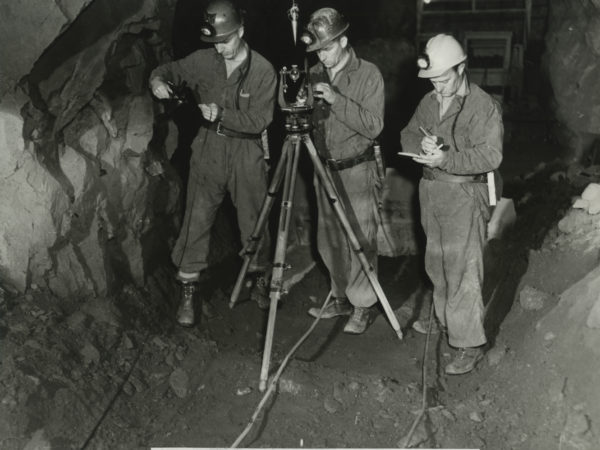 Three men survey a Republic Steel Company mine in Mineville