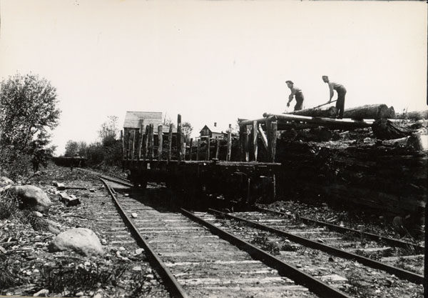 Men load logs onto railroad flatcar in McKeever