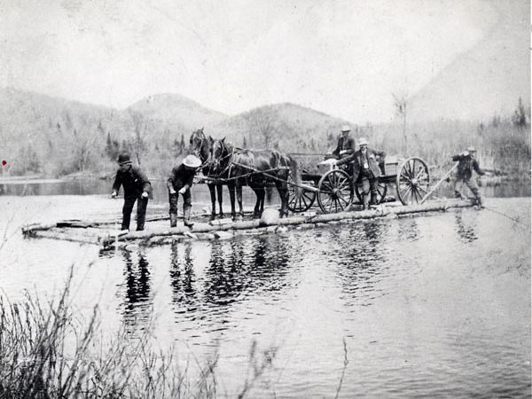 Men ferry a wagon across Cedar River in Indian Lake