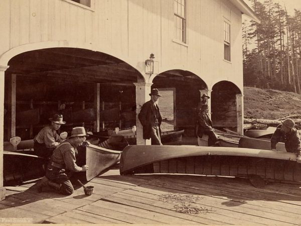 Men with canoes at a boathouse in Paul Smiths