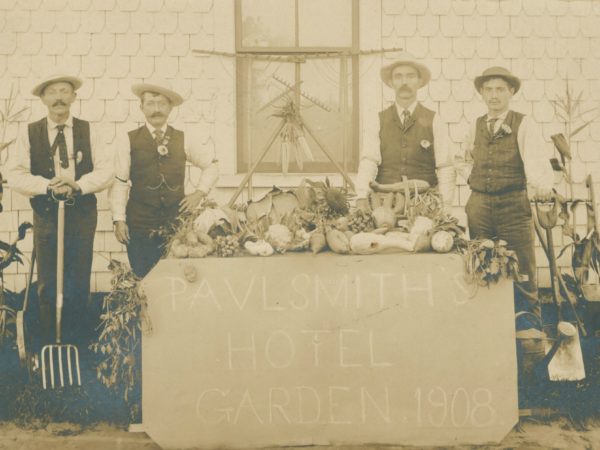 Men with a table of vegetables from the garden at Paul Smith’s Hotel in Paul Smiths