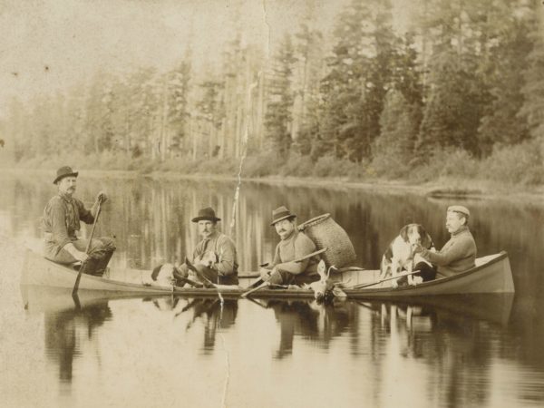 Guides with dogs and deer in a guideboat in Paul Smiths