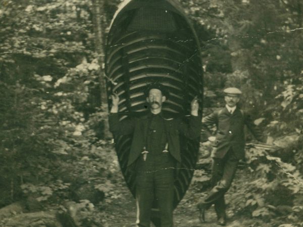 Guide carries a boat through the woods in the Adirondacks