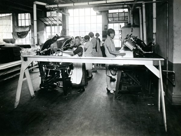 Workers using machines at the Geo Sweetser & Son Shirt Factory in Watertown