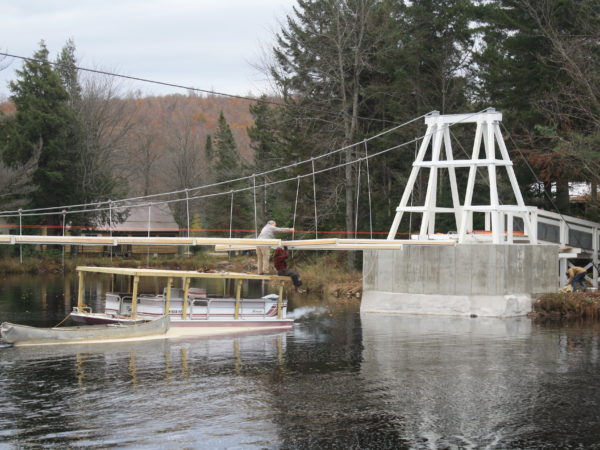 Carrying lumber for the Wanakena footbridge on a pontoon boat