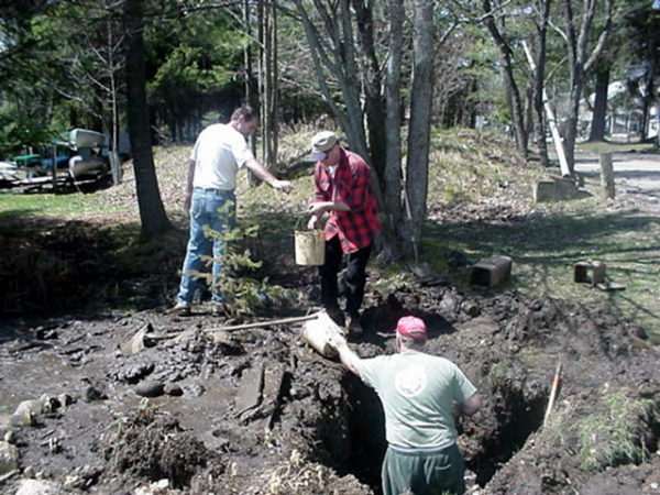 Three volunteers fix a break in the water system in Wanakena