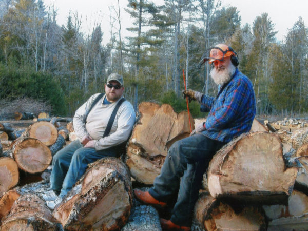 Philip N. Jackson IV, right, and Jack Pulsifer sit on a pile of large, soft maple logs. They were cut close to the Boquet River. Spring 2016. Elizabethtown, NY. Courtesy of Phil Jackson.