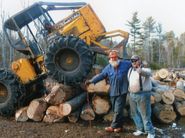 Two lumberjacks posing next to a pile of logs in Elizabethtown