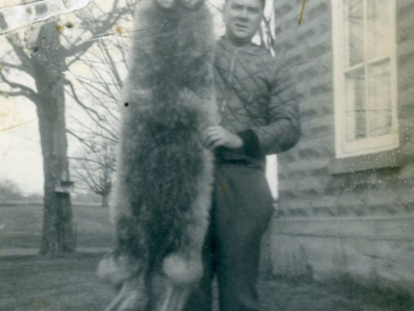 Trapper posing with a red coyote pelt in Morristown