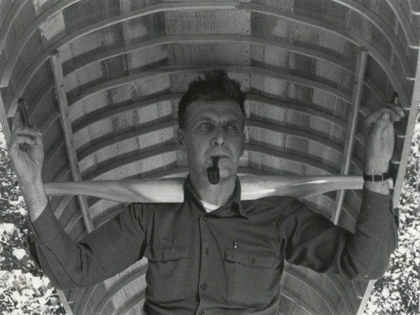 Guideboat builder Carl Hathaway carrying a guideboat in Saranac Lake