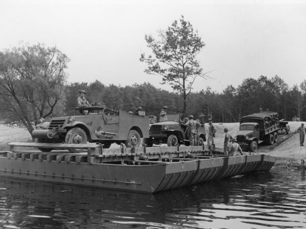 Soldiers loading vehicles and equipment onto a barge at Pine Camp