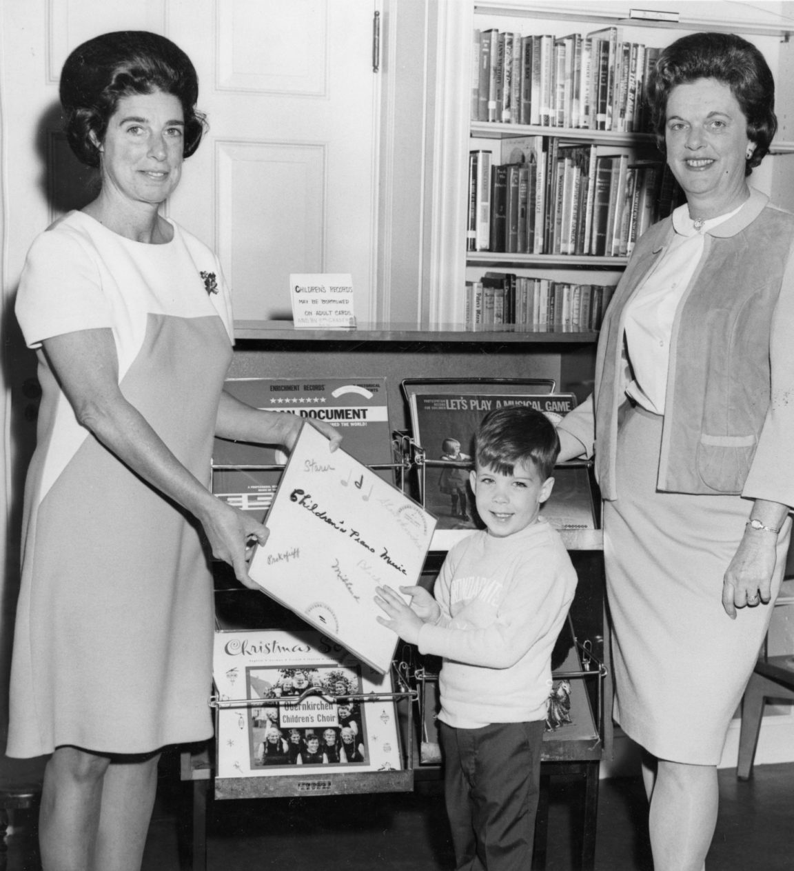 Library staff help child check out record at Crandall Public Library in