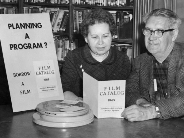 Librarian McAndrews shows film catalog to a patron at the Crandall Public Library in Glens Falls