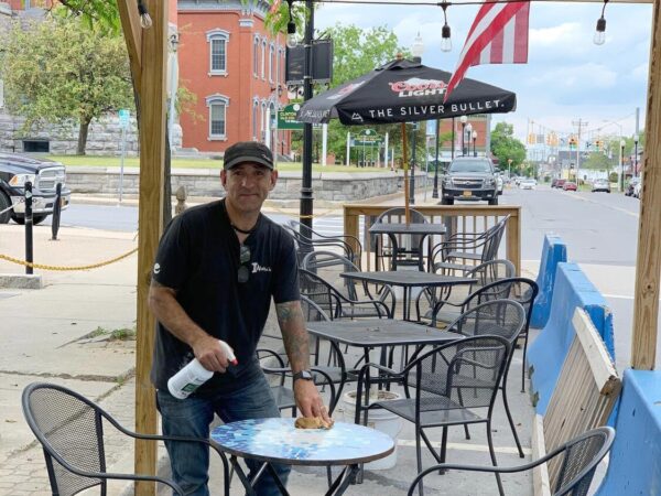 Peter Kritziotis wiping down a table in Aleka's outdoor dining space.