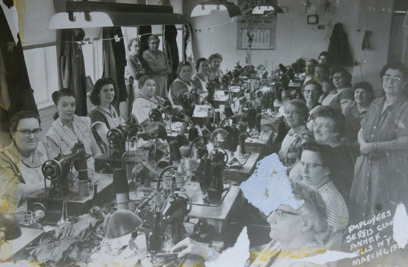 Women sit at work tables in glove factory