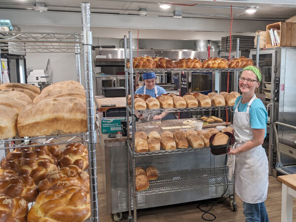 Woman stands with loaves of bread