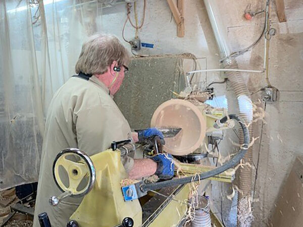 A man carving a bowl on a lathe